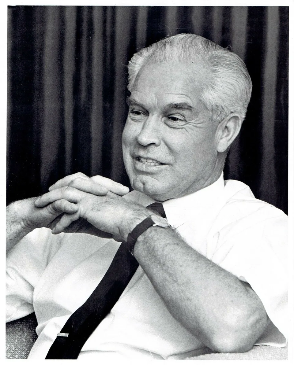 Black-and-white portrait of William Hanna seated with his hands clasped beneath his chin.