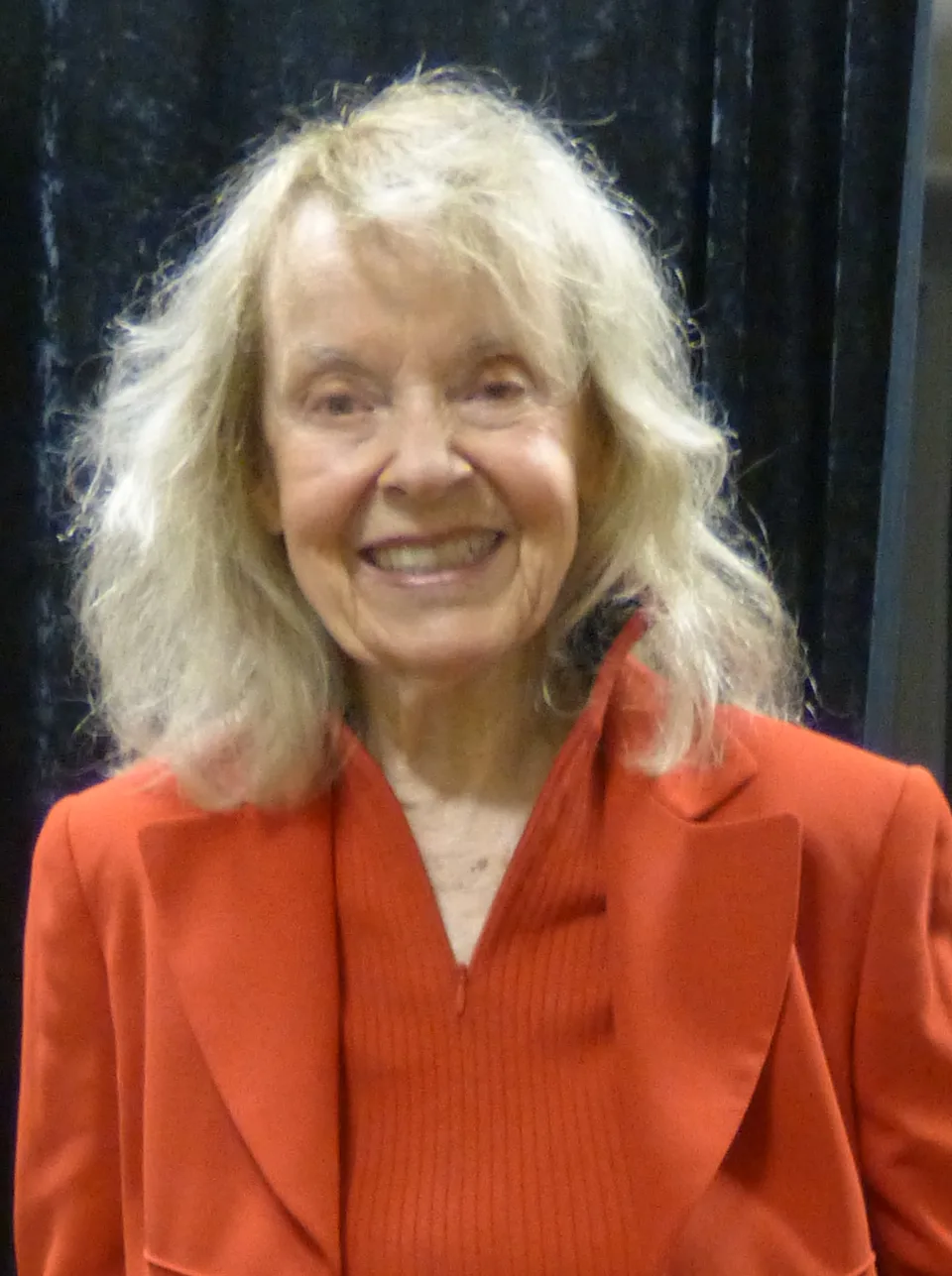 Janet Waldo smiles in a bright red jacket.