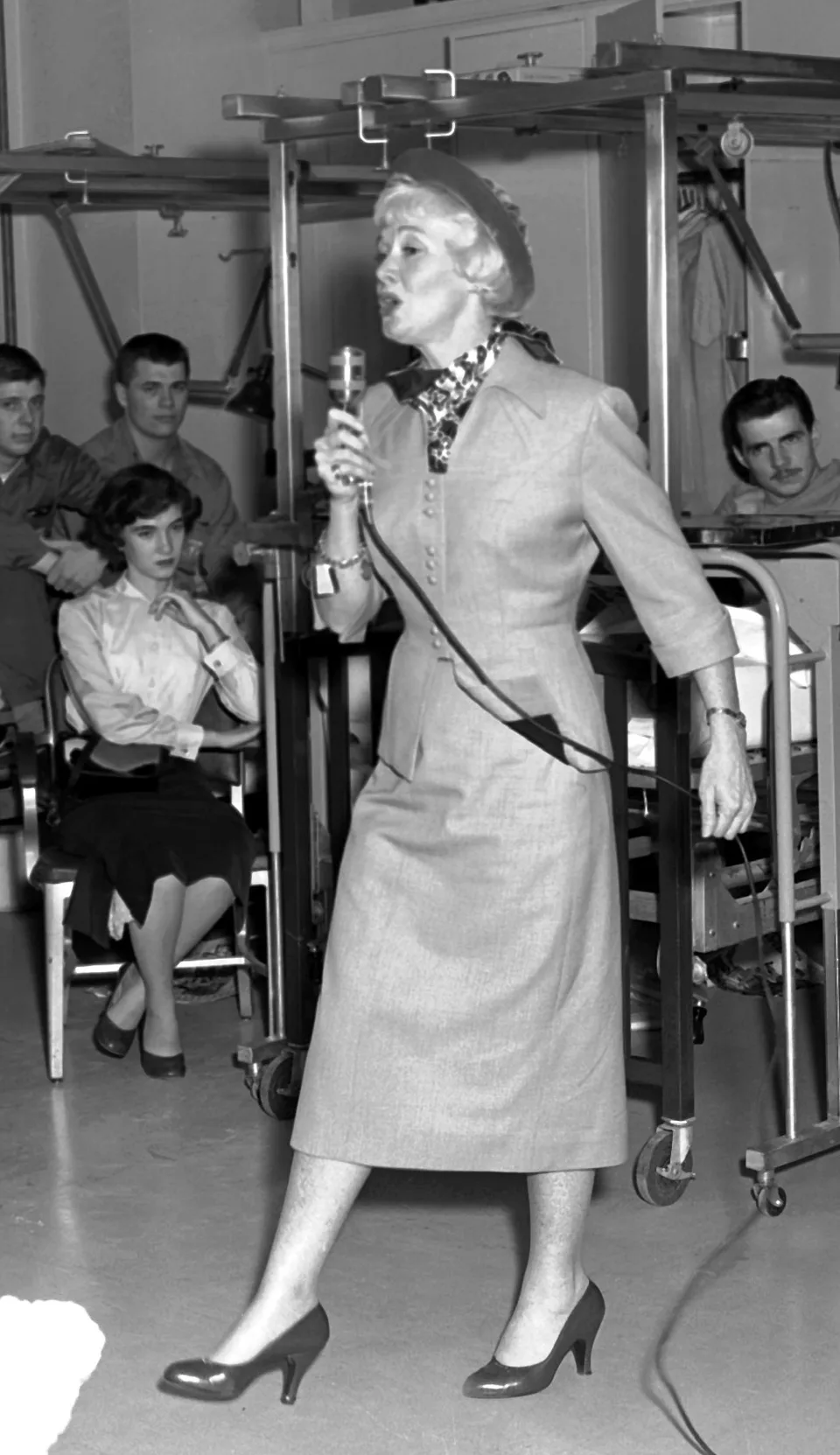 Penny Singleton performs with a handheld microphone in a hospital ward.