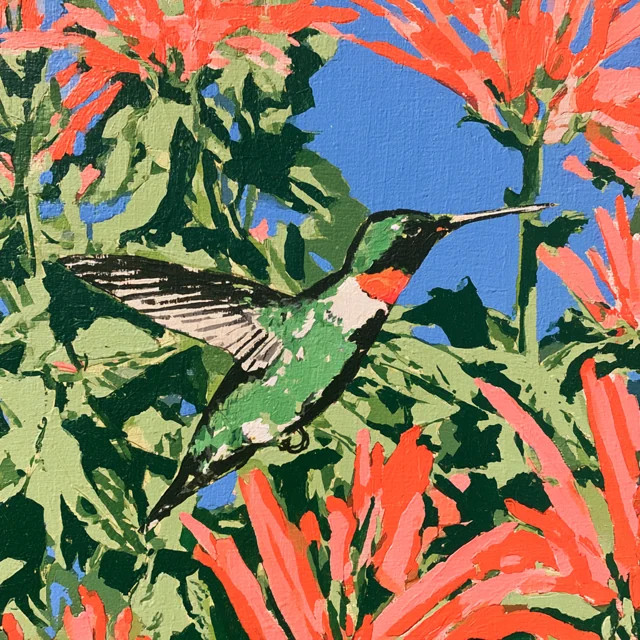 A tiny hummingbird flies through green foliage and bright coral blooms with blue sky behind.