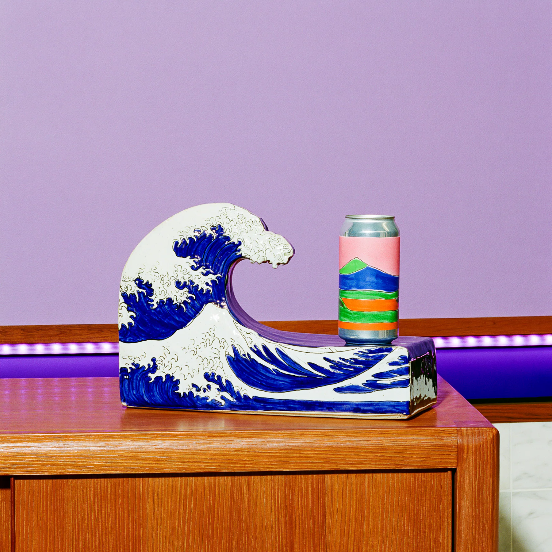 A deep blue crescent wave pedestal against a lilac wall